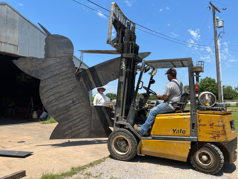 Hummingbird piece of the sculpture lifted by a forklift 