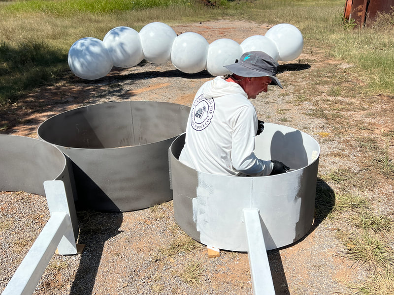 Ty Tompkins sitting inside the Chrysalis Circles, painting it white